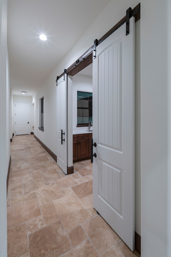 Photo of a large mediterranean dedicated laundry room in Orlando with an integrated sink, raised-panel cabinets, brown cabinets, granite benchtops, white walls, travertine floors, a side-by-side washer and dryer, beige floor and white benchtop.