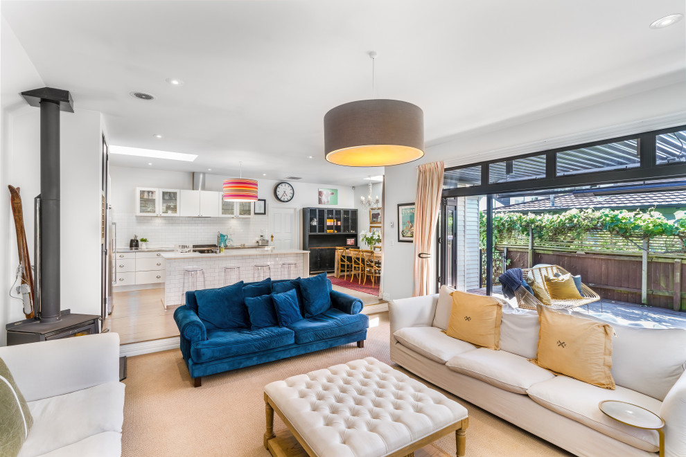 Photo of a Mid-sized shabby-chic style Open Concept living room in Christchurch With White Walls, Carpet, a Corner Fireplace, a Wall-mounted TV and Brown Floor.