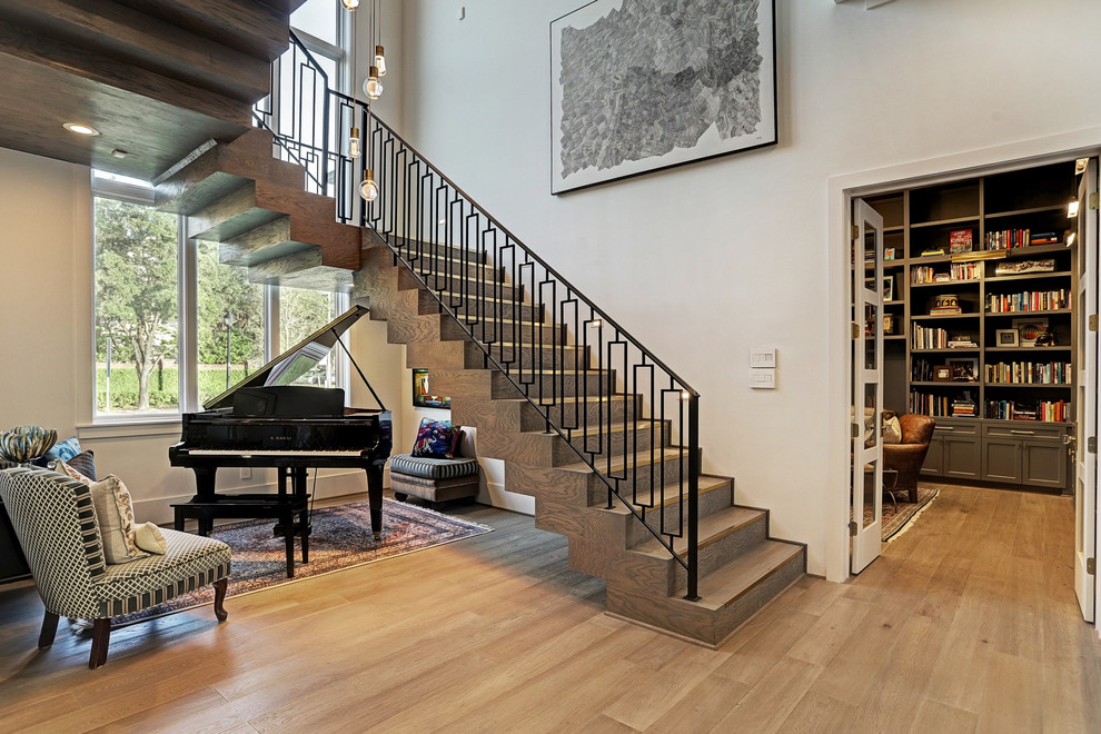Expansive transitional wood floating staircase in Houston with wood risers and metal railing.