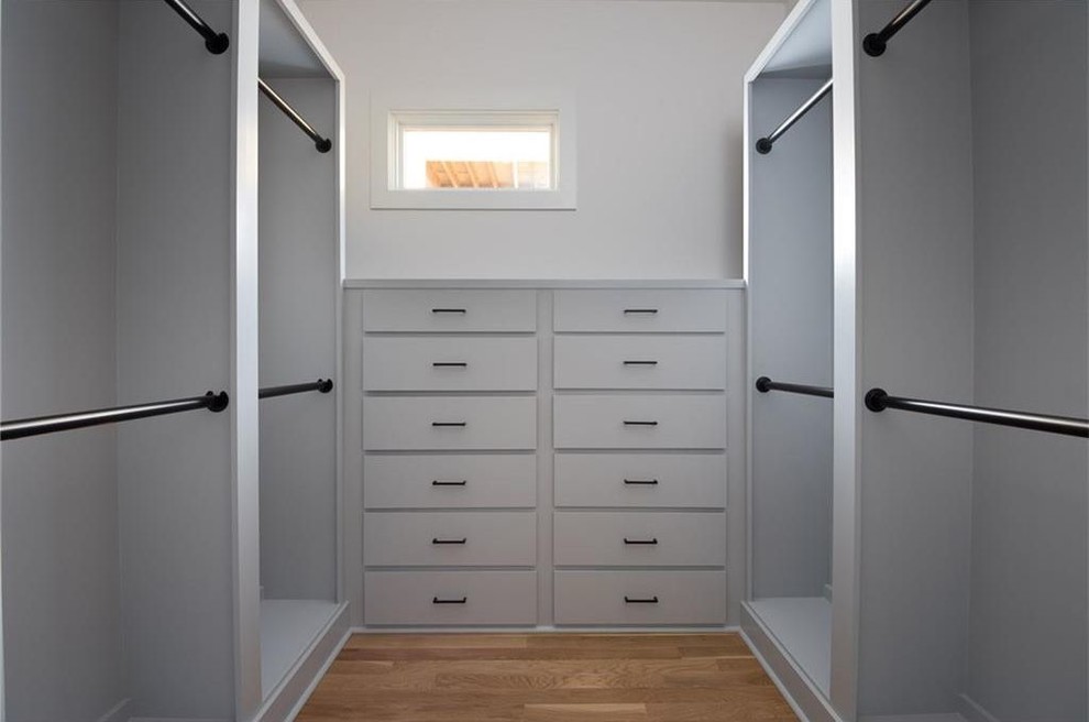 Mid-sized modern gender-neutral dressing room in Atlanta with beaded inset cabinets, white cabinets, medium hardwood floors and beige floor.