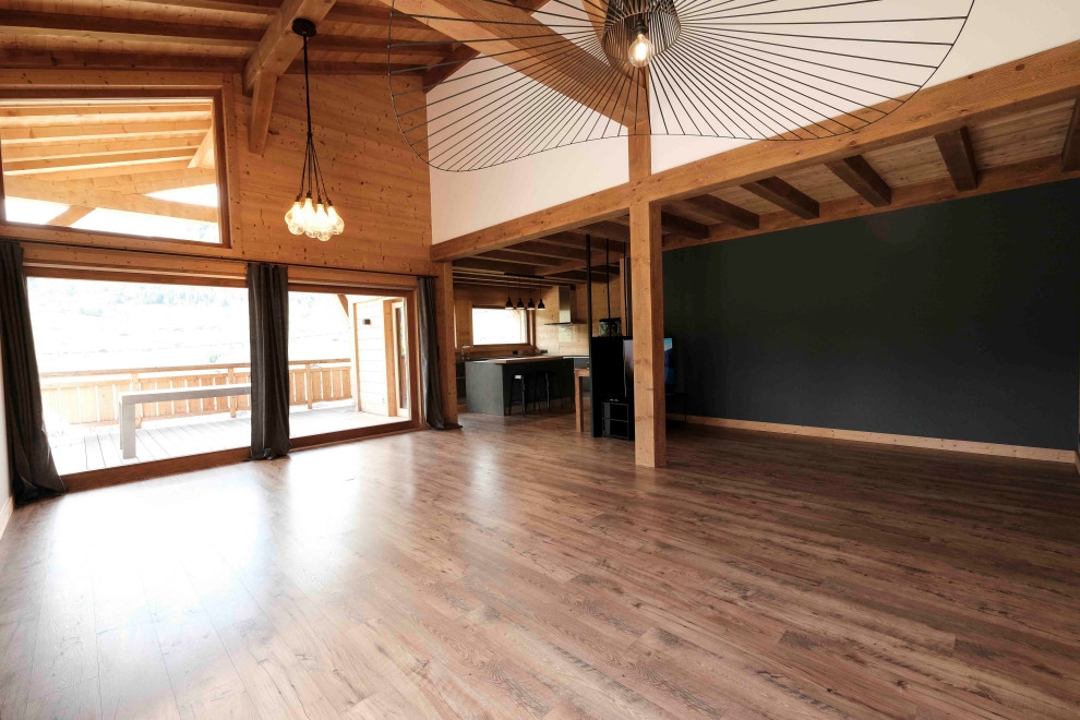 Ejemplo de salón abierto y blanco y madera rústico grande sin chimenea con paredes negras, suelo laminado, televisor retractable, suelo marrón, madera y madera