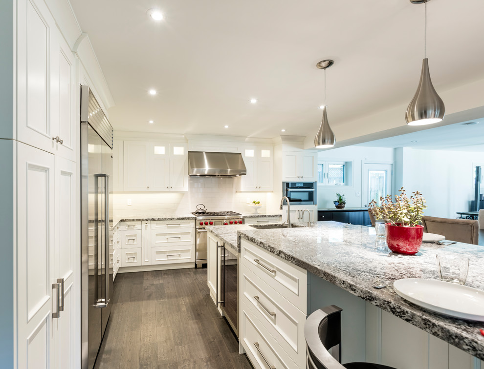 Example of a mid-sized transitional brown floor kitchen design in Toronto with white cabinets, stainless steel appliances and an island