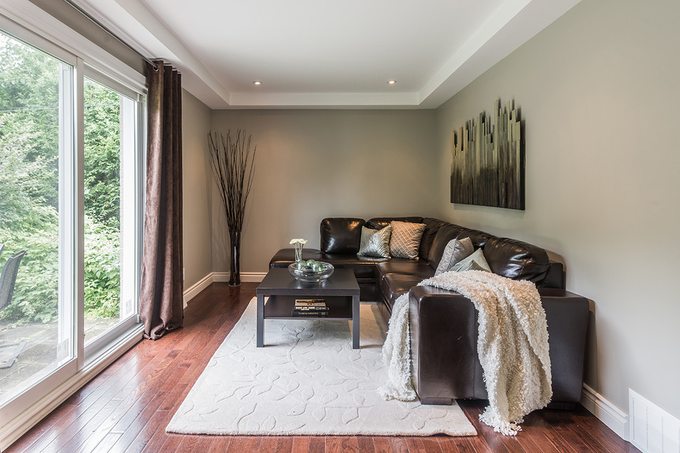 Photo of a mid-sized contemporary enclosed family room in Montreal with dark hardwood floors and grey walls.