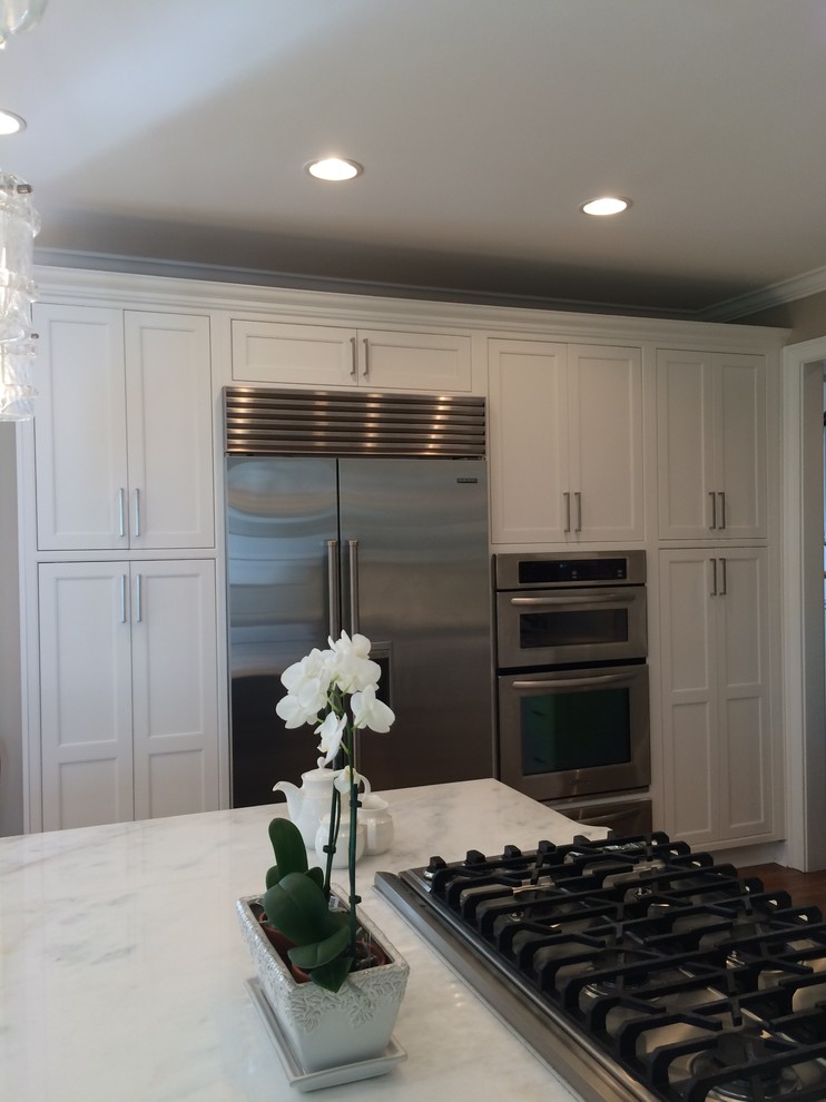 Example of a large transitional dark wood floor kitchen design in Atlanta with a single-bowl sink, beaded inset cabinets, white cabinets, marble countertops, white backsplash, stainless steel appliances and an island
