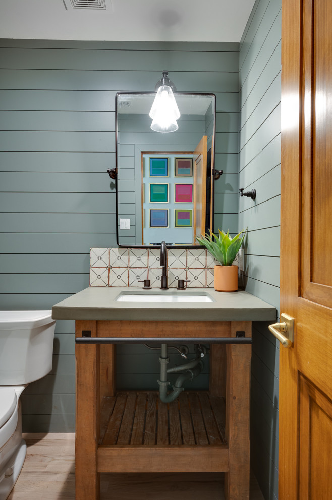 This is an example of a small traditional cloakroom in Dallas with open cabinets, brown cabinets, a two-piece toilet, ceramic tiles, light hardwood flooring, a submerged sink, concrete worktops, beige worktops, a freestanding vanity unit and panelled walls.