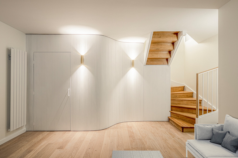 Photo of a large contemporary wood u-shaped mixed railing staircase in Paris with painted wood risers, wood walls and under stair storage.