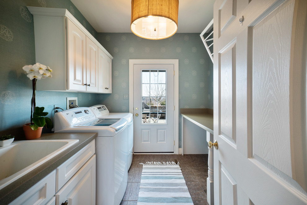 This is an example of a mid-sized traditional galley dedicated laundry room in Philadelphia with a single-bowl sink, raised-panel cabinets, white cabinets, quartzite benchtops, blue walls, porcelain floors, a side-by-side washer and dryer and grey benchtop.