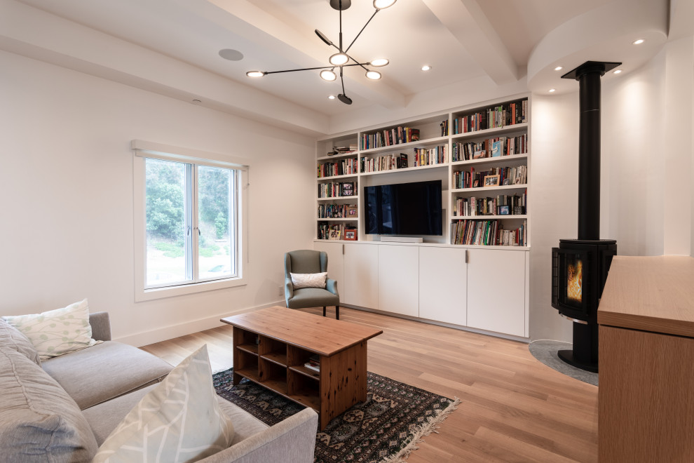 Imagen de biblioteca en casa abierta tradicional renovada de tamaño medio con suelo de madera en tonos medios, estufa de leña, pared multimedia, suelo marrón y casetón