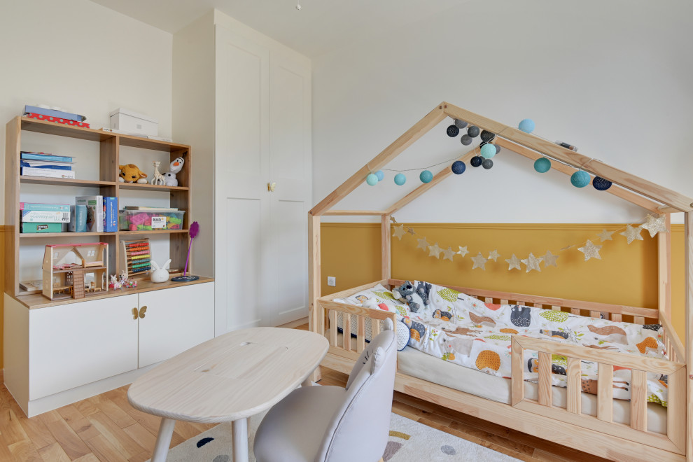 Immagine di una grande cameretta per bambini da 4 a 10 anni contemporanea con pareti gialle, parquet chiaro, pavimento beige e boiserie