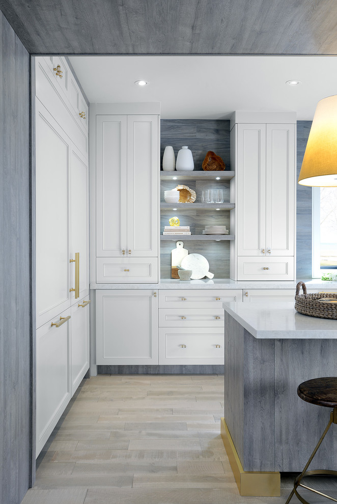 Inspiration for a mid-sized transitional u-shaped light wood floor and gray floor open concept kitchen remodel in Toronto with an undermount sink, shaker cabinets, white cabinets, solid surface countertops, stainless steel appliances and an island