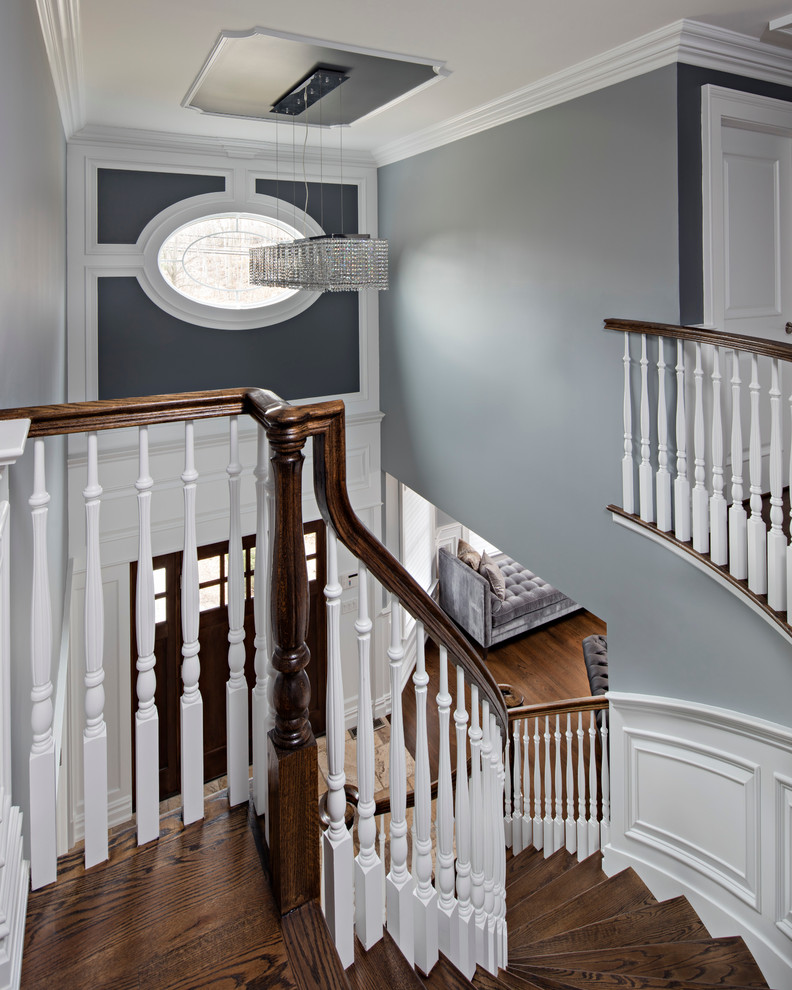 Photo of a large traditional wood curved staircase in New York with painted wood risers.