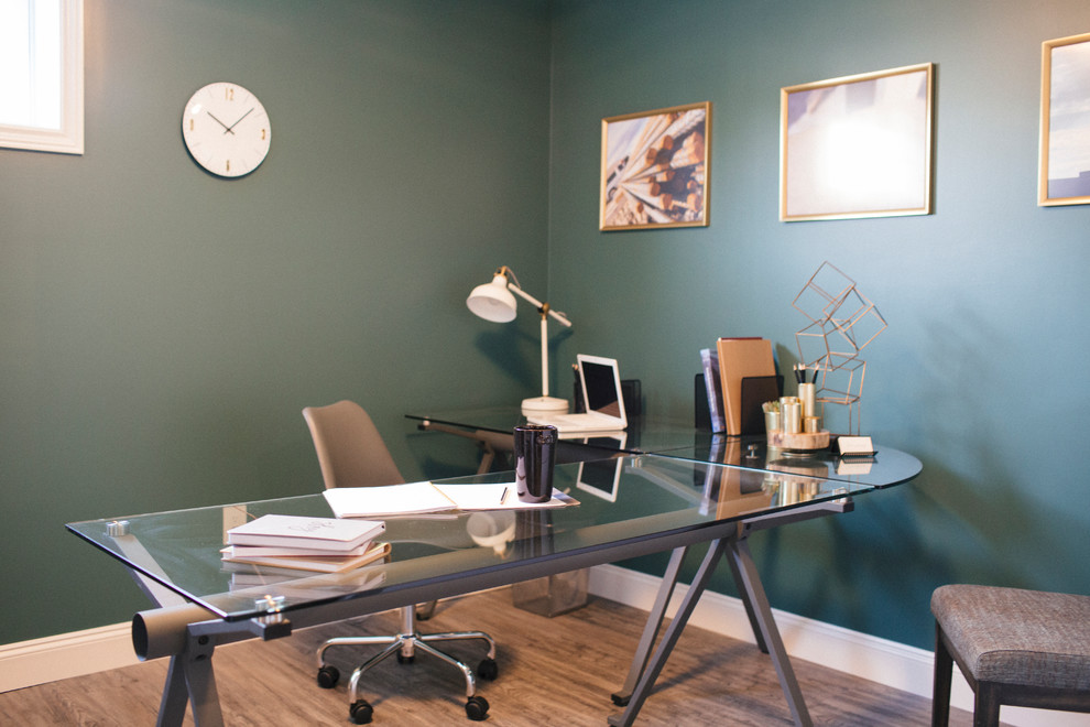 Mid-sized industrial study room with green walls, medium hardwood floors, a freestanding desk and brown floor.