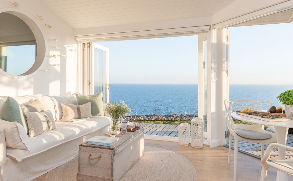 Design ideas for a small nautical open plan living room in Cornwall with white walls, light hardwood flooring, a standard fireplace, a metal fireplace surround, a wall mounted tv and beige floors.