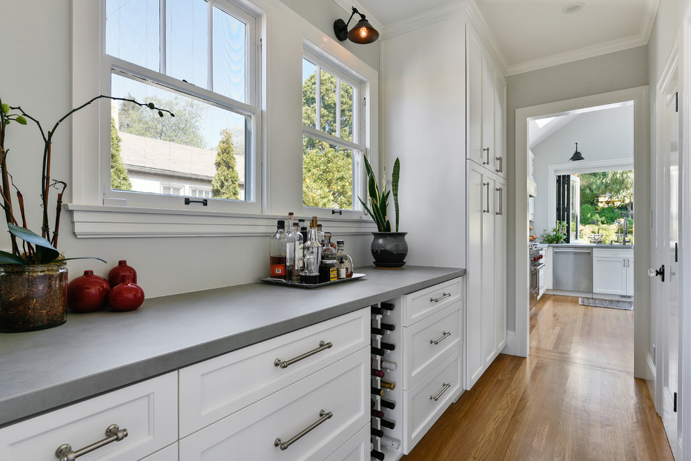 Design ideas for a mid-sized transitional u-shaped open plan kitchen in San Francisco with an undermount sink, shaker cabinets, white cabinets, concrete benchtops, white splashback, marble splashback, stainless steel appliances, medium hardwood floors, with island, brown floor and grey benchtop.