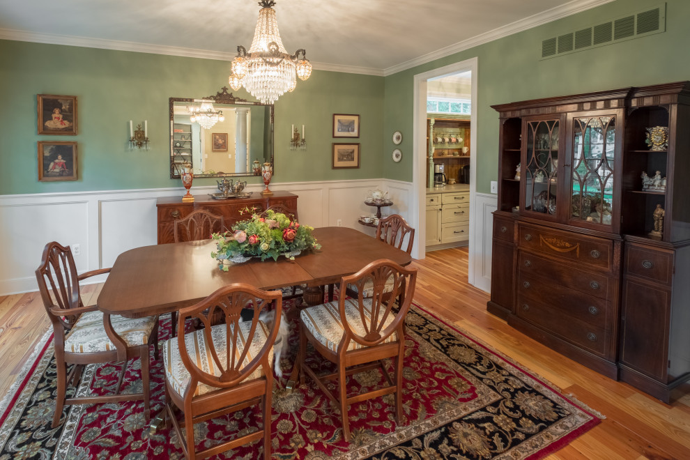 This is an example of a mid-sized country separate dining room in Detroit with green walls, light hardwood floors, brown floor and decorative wall panelling.