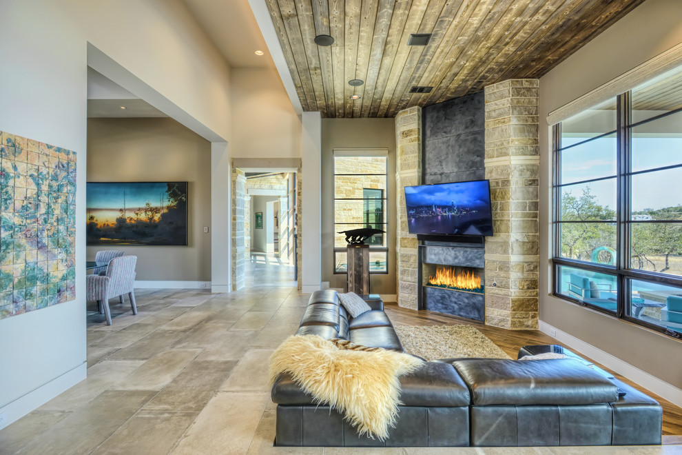This is an example of a mid-sized modern open concept family room in Houston with beige walls, ceramic floors, a corner fireplace, a metal fireplace surround, a wall-mounted tv and grey floor.