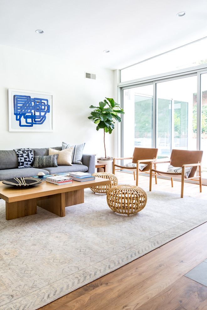 Inspiration for a midcentury open concept living room in Los Angeles with white walls, medium hardwood floors, a two-sided fireplace, a tile fireplace surround and brown floor.