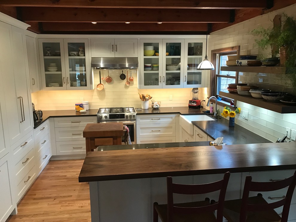 Eat-in kitchen - mid-sized transitional eat-in kitchen idea with a farmhouse sink, white cabinets, quartz countertops, white backsplash, glass tile backsplash and stainless steel appliances