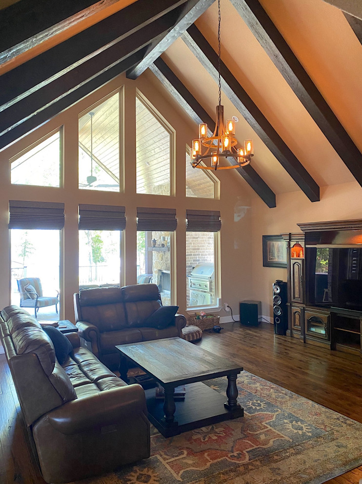 Photo of a mid-sized arts and crafts open concept living room in Dallas with brown walls, medium hardwood floors, a two-sided fireplace, a wall-mounted tv, brown floor and vaulted.