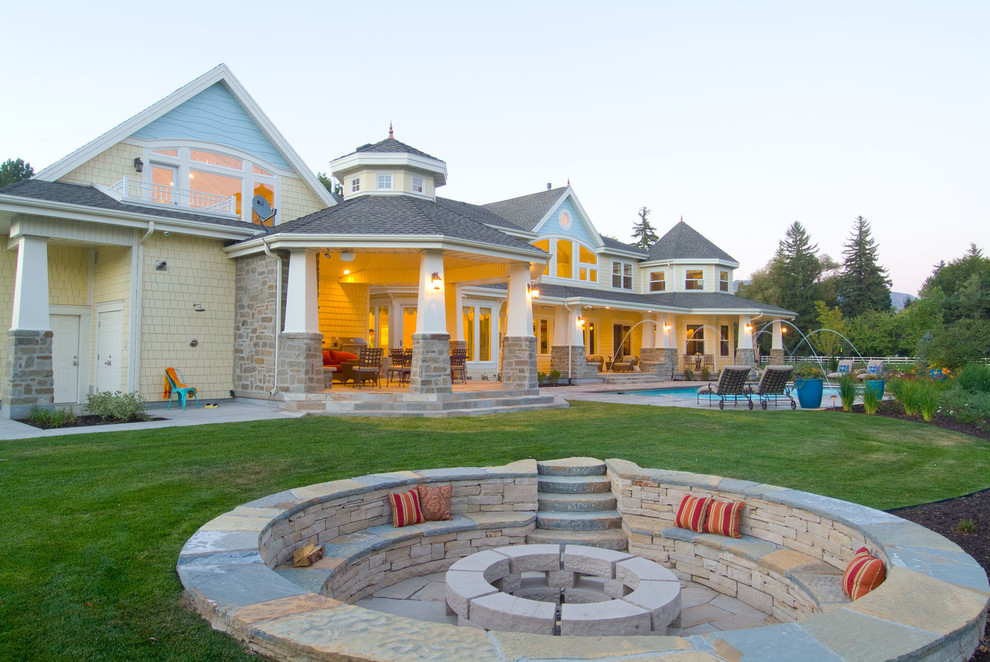 Design ideas for an expansive traditional backyard patio in Salt Lake City with a fire feature, natural stone pavers and a roof extension.