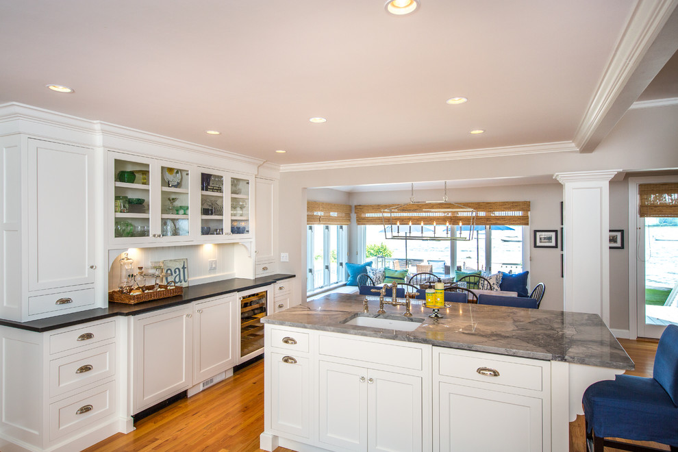 Kitchen - transitional medium tone wood floor kitchen idea in Boston with a farmhouse sink, recessed-panel cabinets, white cabinets, granite countertops, white backsplash, subway tile backsplash, stainless steel appliances and two islands