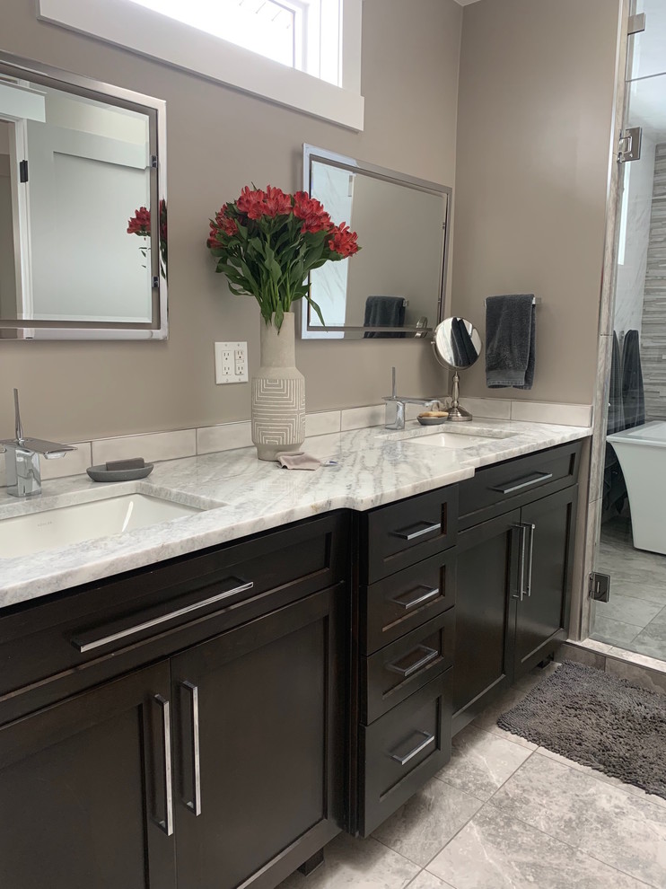 Inspiration for a contemporary master wet room bathroom in Denver with shaker cabinets, black cabinets, a freestanding tub, gray tile, marble, beige walls, an undermount sink, marble benchtops, grey floor, a hinged shower door and white benchtops.