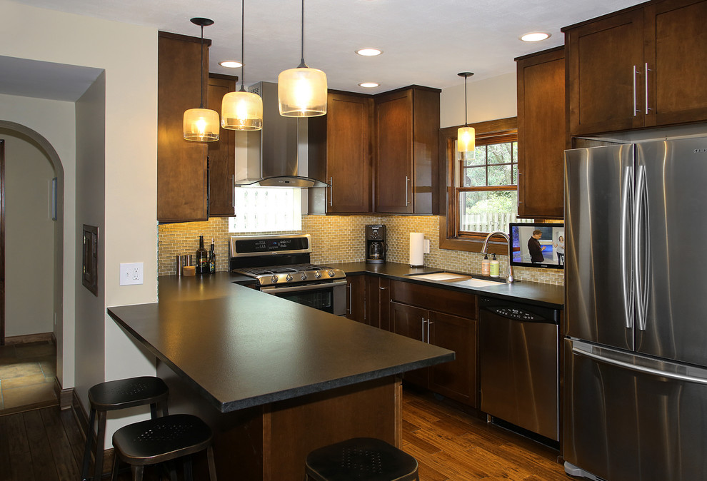Inspiration for a small transitional u-shaped medium tone wood floor kitchen remodel in Chicago with an undermount sink, shaker cabinets, dark wood cabinets, granite countertops, beige backsplash, glass tile backsplash and stainless steel appliances