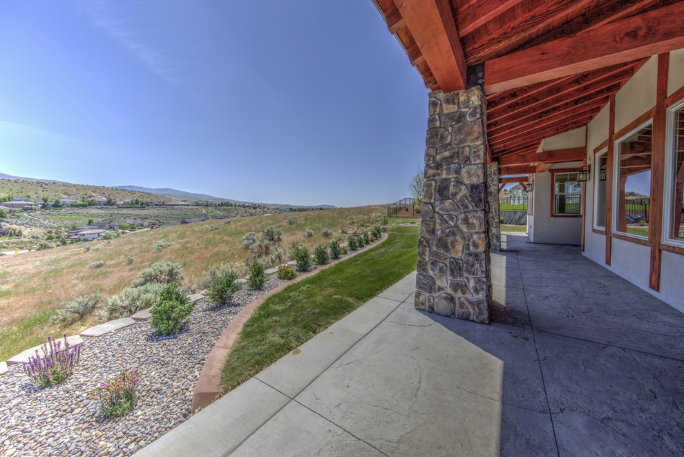 Huge mountain style backyard deck photo in Boise with a roof extension