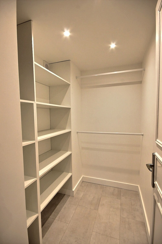 This is an example of a medium sized modern gender neutral dressing room in Other with open cabinets, white cabinets, vinyl flooring and grey floors.