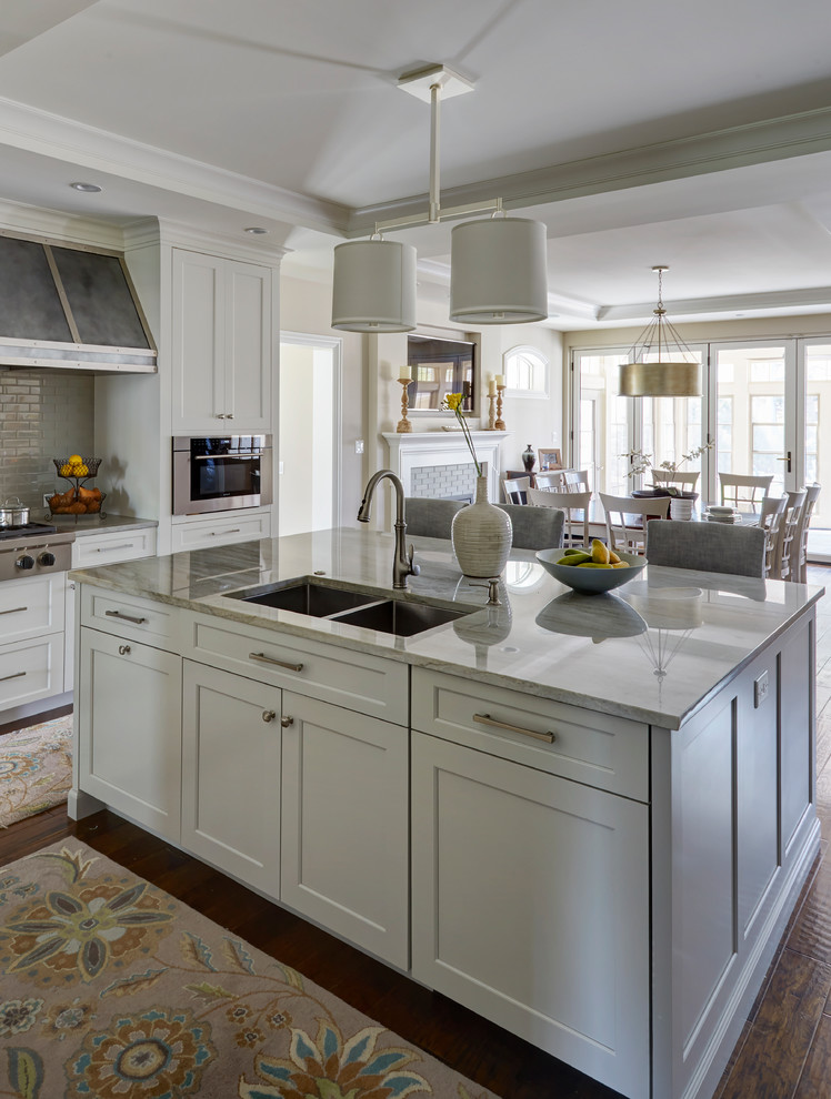 Inspiration for a mid-sized transitional u-shaped dark wood floor and brown floor open concept kitchen remodel in Chicago with an undermount sink, shaker cabinets, white cabinets, marble countertops, gray backsplash, ceramic backsplash, stainless steel appliances, an island and beige countertops