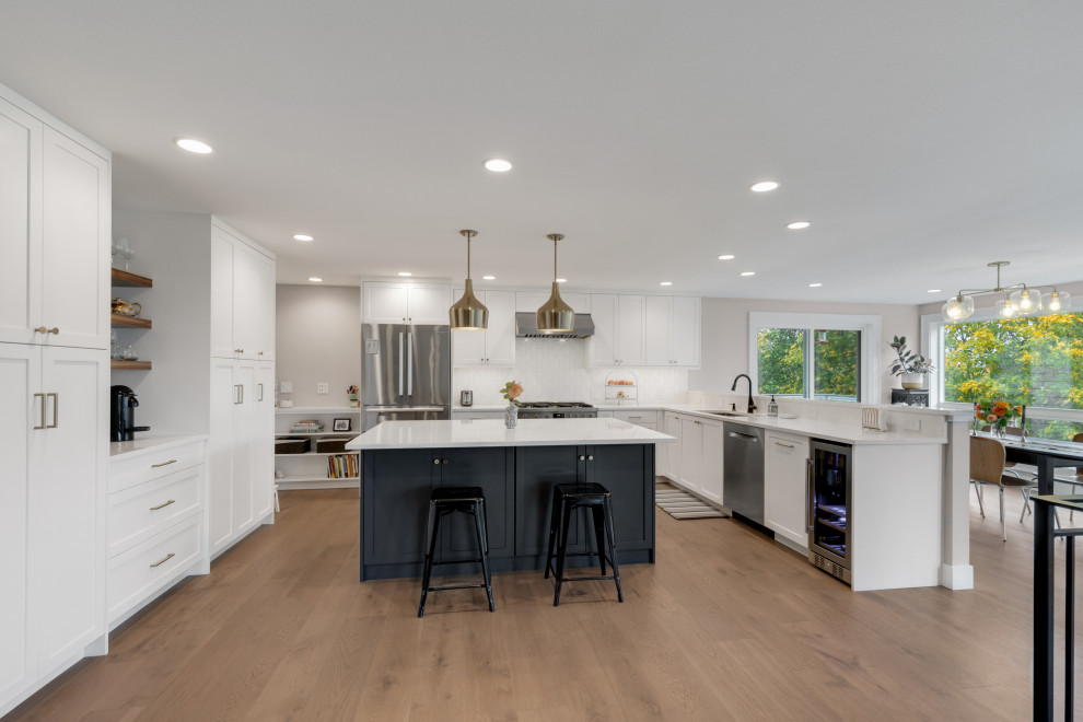 Inspiration for a mid-sized mid-century modern u-shaped medium tone wood floor eat-in kitchen remodel in Seattle with an undermount sink, shaker cabinets, white cabinets, quartz countertops, white backsplash, ceramic backsplash, stainless steel appliances, an island and white countertops