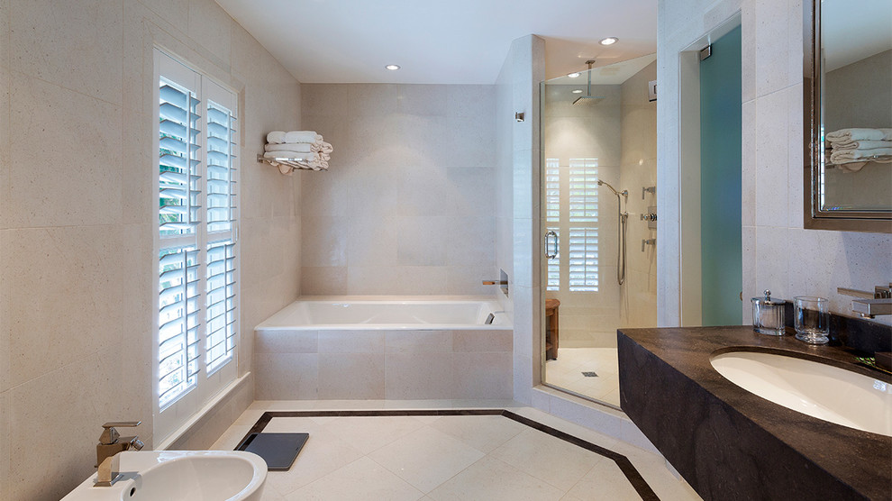 This is an example of a mid-sized beach style master bathroom in Other with an alcove tub, a corner shower, a bidet, beige tile, marble, beige walls, porcelain floors, an undermount sink, solid surface benchtops, beige floor, a hinged shower door and brown benchtops.