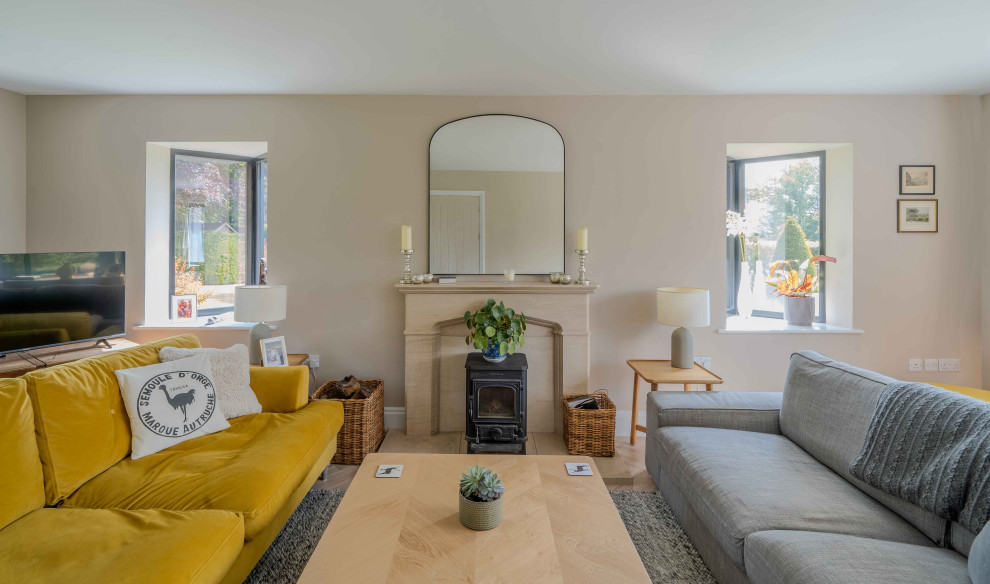 This is an example of a medium sized classic formal enclosed living room in Hampshire with beige walls, carpet, a wood burning stove, a stone fireplace surround, a freestanding tv and grey floors.