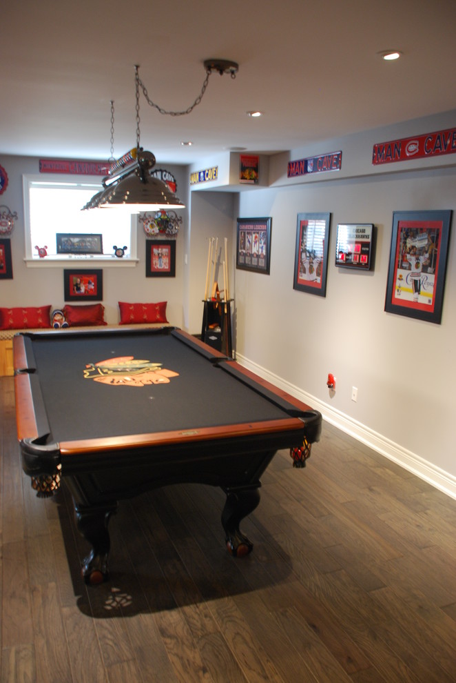 This is an example of a mid-sized eclectic open concept family room in Toronto with a game room, grey walls and light hardwood floors.