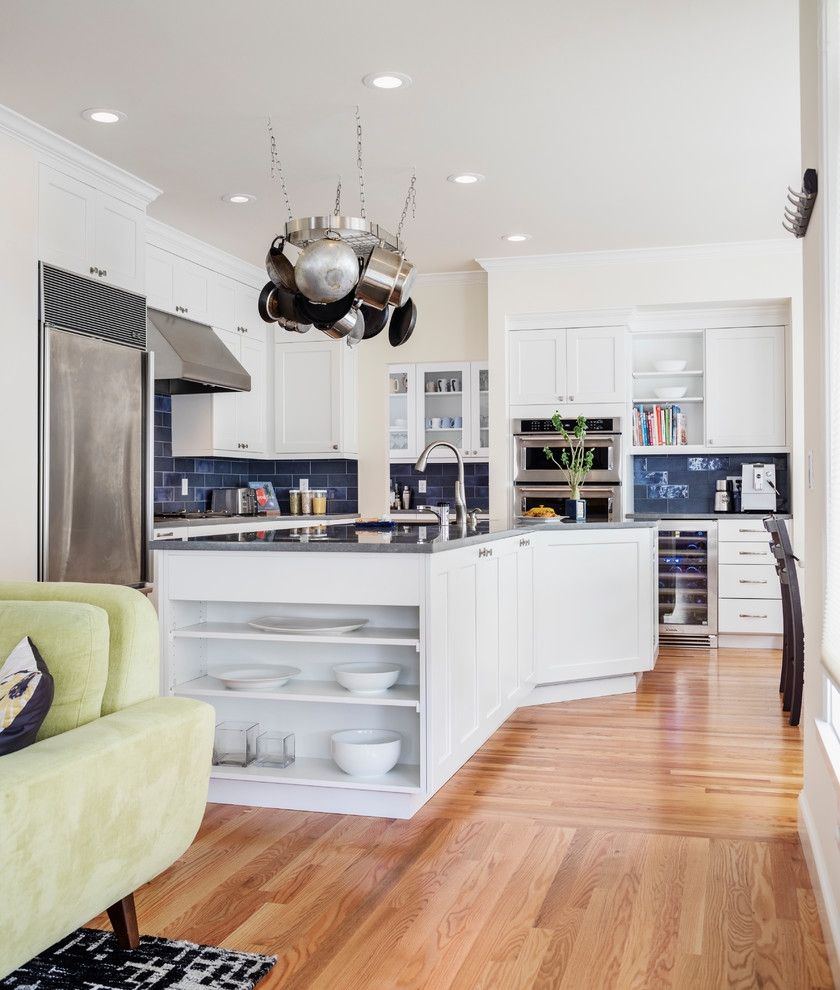 Inspiration for a mid-sized transitional l-shaped open plan kitchen in Seattle with an undermount sink, shaker cabinets, white cabinets, quartz benchtops, blue splashback, ceramic splashback, stainless steel appliances, medium hardwood floors, with island, grey benchtop and brown floor.