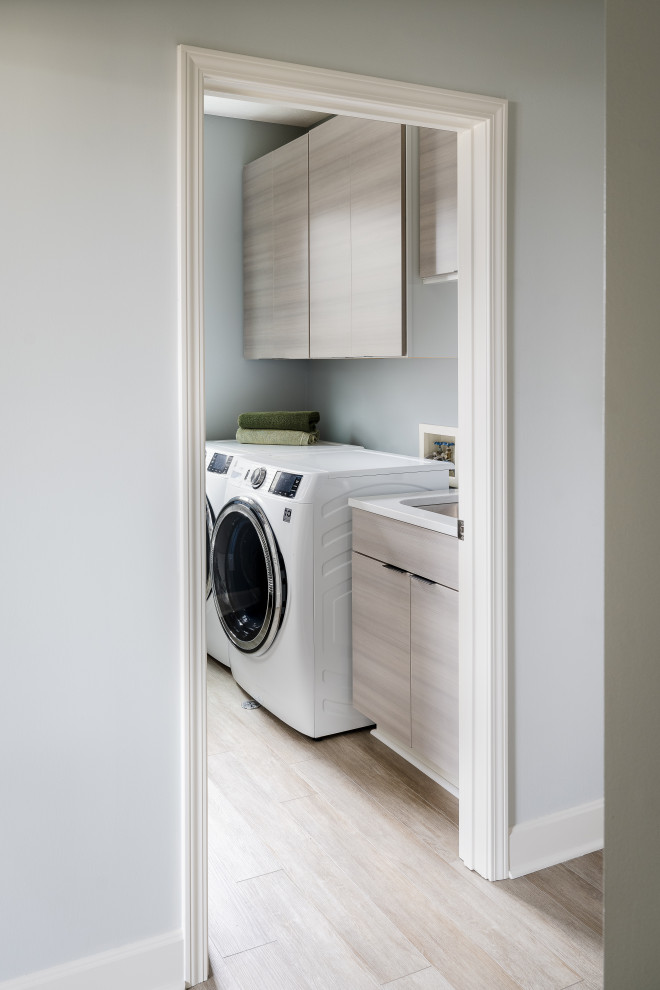 Imagen de cuarto de lavado de galera minimalista de tamaño medio con fregadero bajoencimera, armarios con paneles lisos, puertas de armario de madera clara y lavadora y secadora juntas