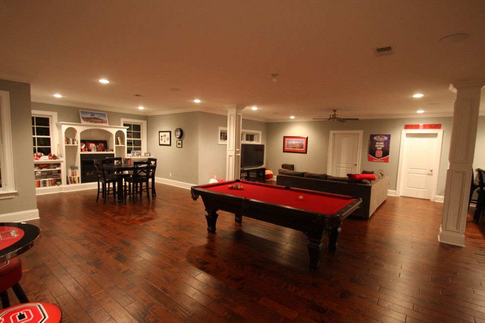 Large traditional look-out basement in Raleigh with grey walls, dark hardwood floors, no fireplace and brown floor.
