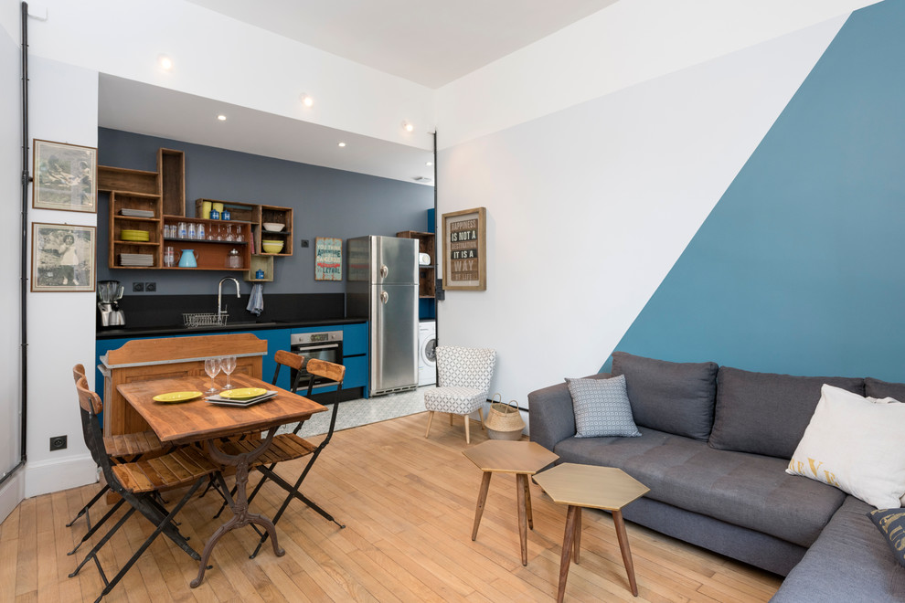 Mid-sized midcentury open concept family room in Lyon with blue walls and light hardwood floors.
