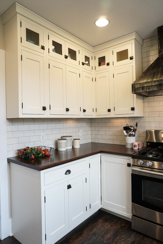Design ideas for a small country u-shaped kitchen pantry in Columbus with a drop-in sink, shaker cabinets, white cabinets, white splashback, subway tile splashback, stainless steel appliances, dark hardwood floors, with island, brown floor and zinc benchtops.