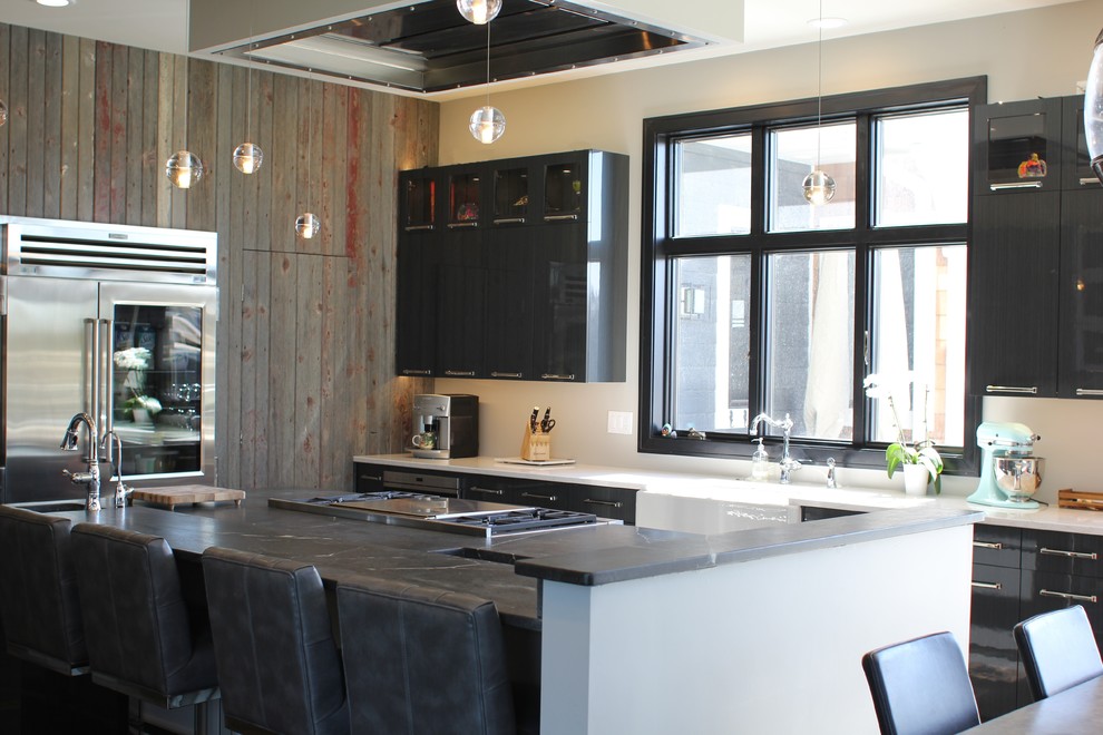 Inspiration for a large rustic u-shaped dark wood floor eat-in kitchen remodel in Cedar Rapids with a farmhouse sink, flat-panel cabinets, black cabinets, solid surface countertops, stainless steel appliances and an island