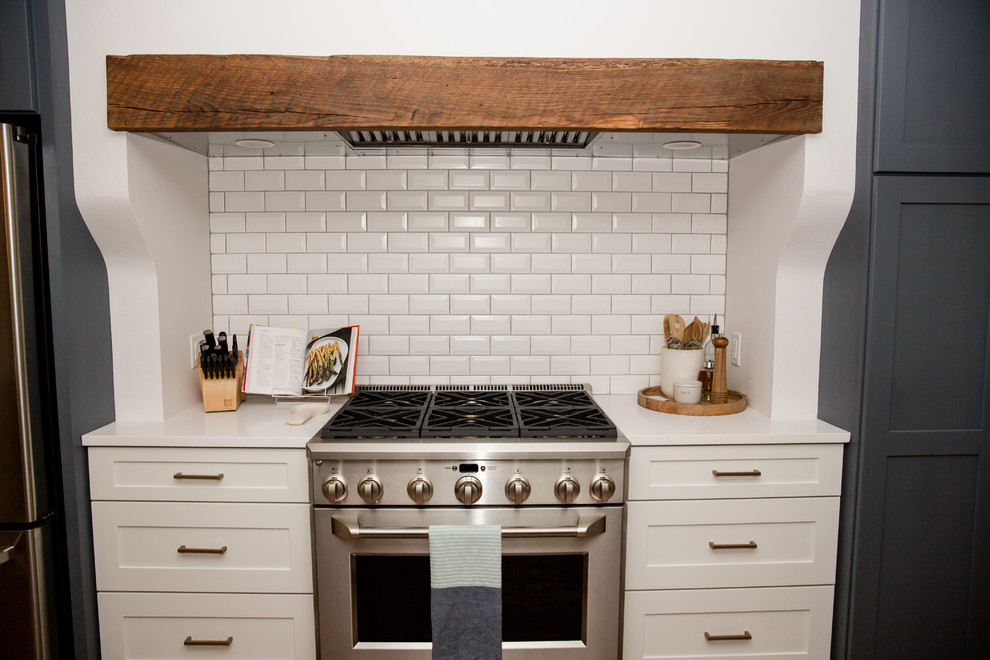 Inspiration for a mid-sized transitional galley medium tone wood floor and brown floor eat-in kitchen remodel with an undermount sink, shaker cabinets, white cabinets, solid surface countertops, white backsplash, ceramic backsplash, stainless steel appliances, a peninsula and white countertops
