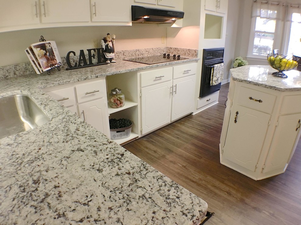Example of a mid-sized classic u-shaped vinyl floor eat-in kitchen design in San Diego with an undermount sink, flat-panel cabinets, yellow cabinets, granite countertops, white backsplash, black appliances and an island