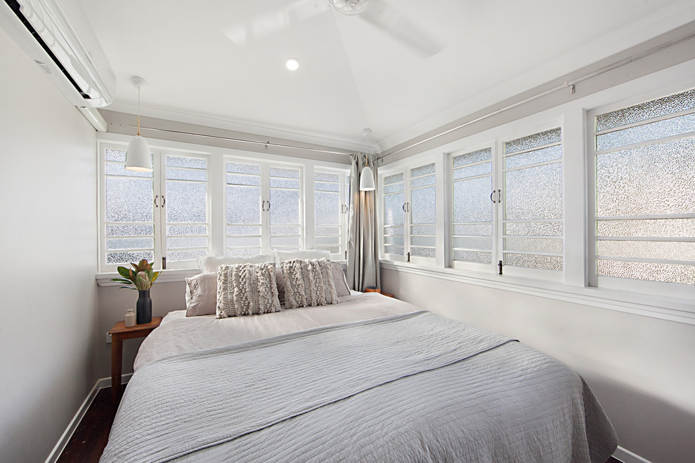 Design ideas for a small beach style master bedroom in Townsville with beige walls and medium hardwood floors.