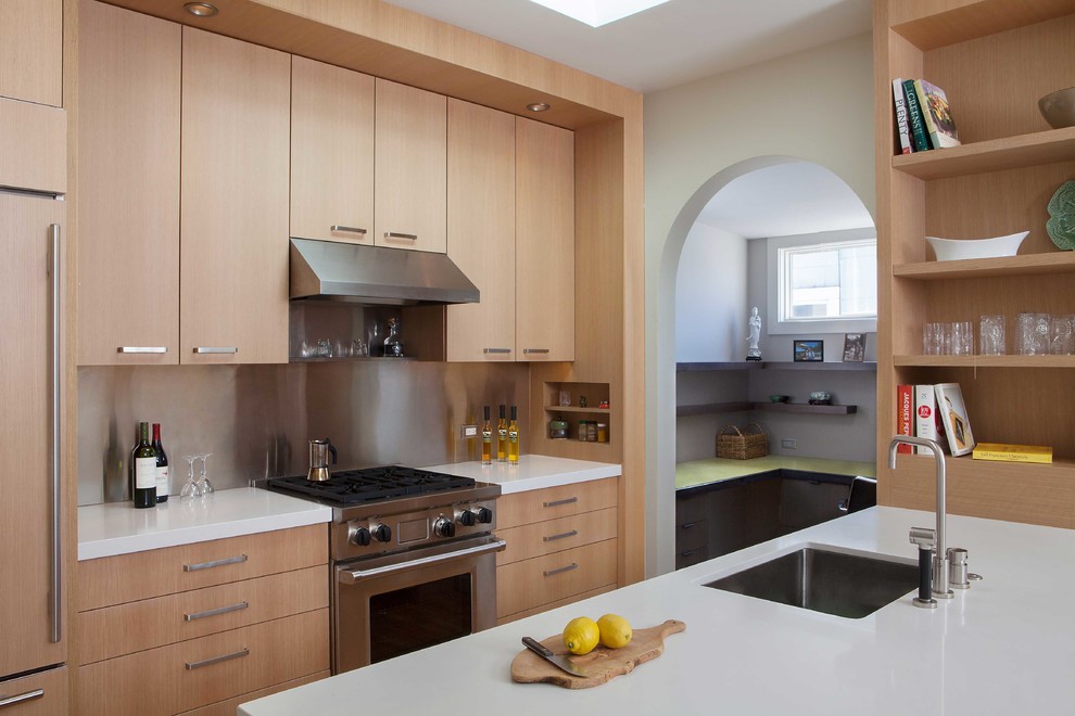 This is an example of a small modern u-shaped kitchen in San Francisco with an undermount sink, flat-panel cabinets, light wood cabinets, metallic splashback, stainless steel appliances, a peninsula, quartz benchtops and medium hardwood floors.