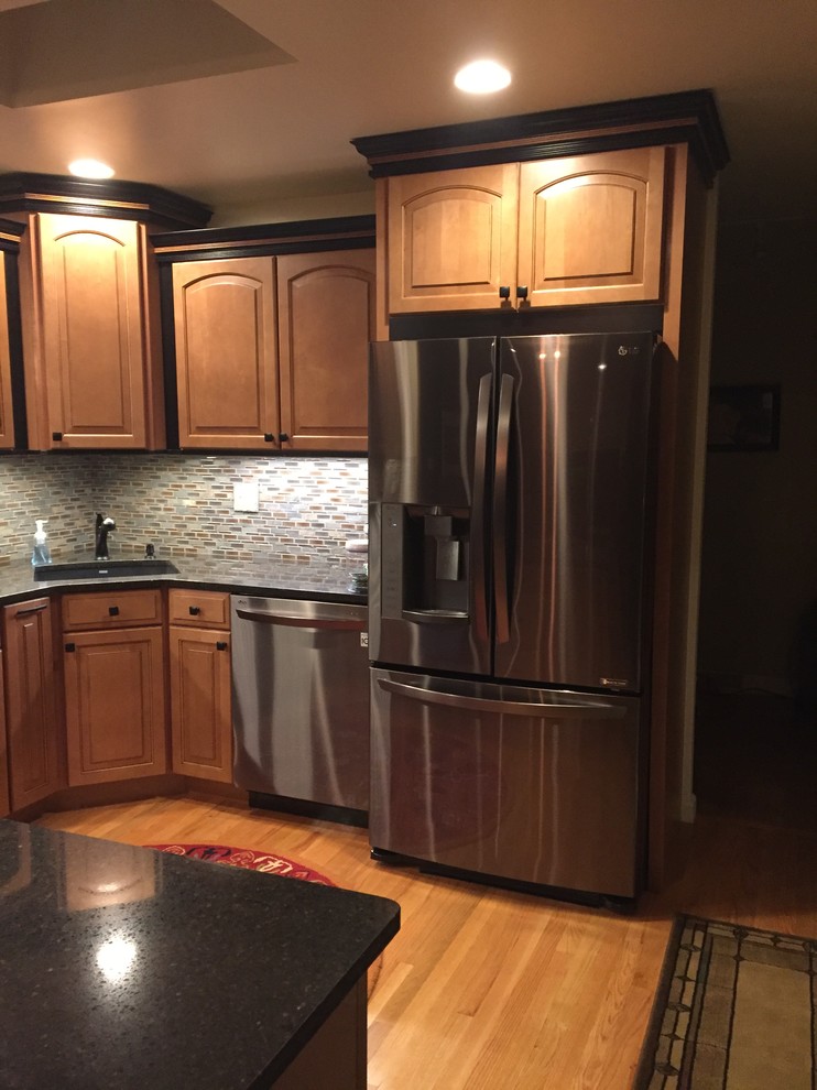 Small mountain style u-shaped light wood floor kitchen photo with a single-bowl sink, raised-panel cabinets, brown cabinets, quartz countertops and mosaic tile backsplash