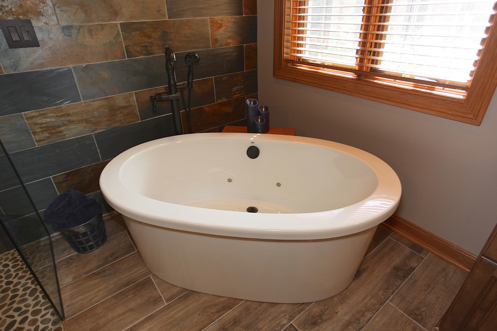 Inspiration for a large rustic master slate tile brown floor freestanding bathtub remodel in Indianapolis with brown cabinets, beige walls and an undermount sink