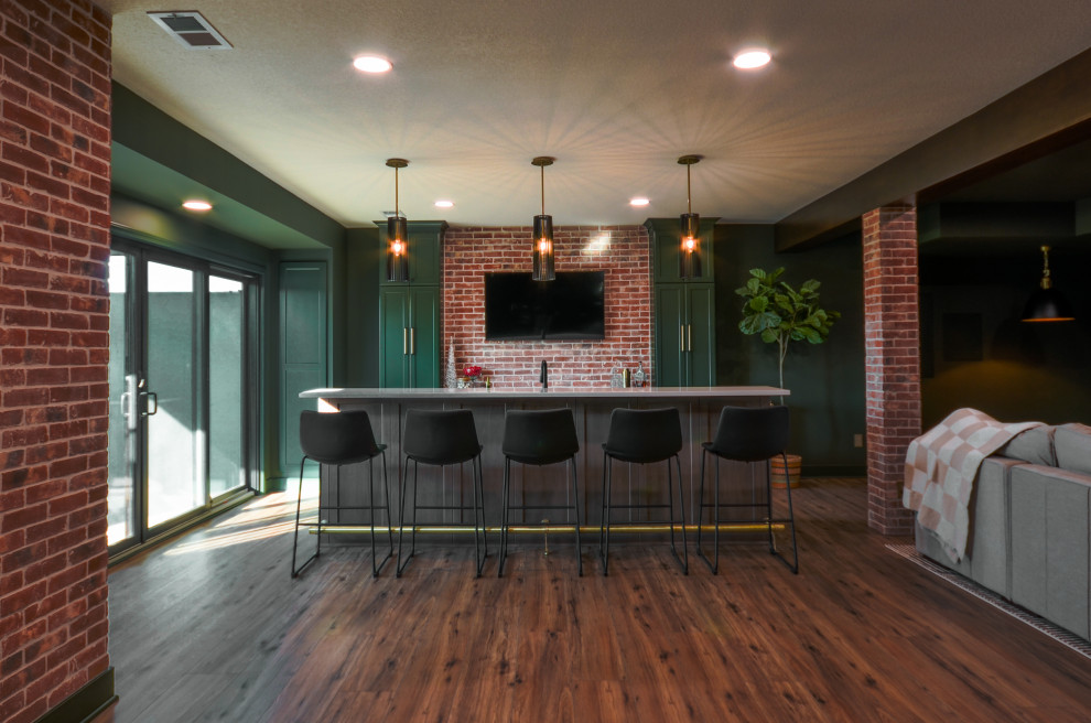Cette image montre un grand sous-sol minimaliste donnant sur l'extérieur avec un bar de salon, un mur vert, un sol en vinyl, poutres apparentes et un mur en parement de brique.