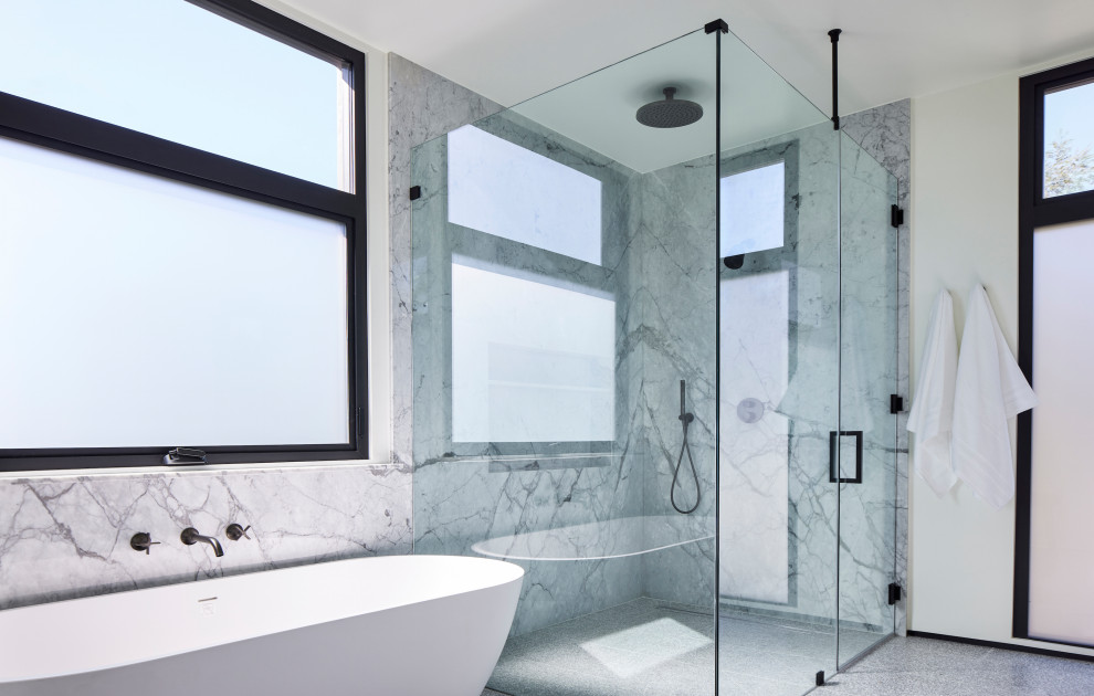 Large modern master bathroom in Los Angeles with flat-panel cabinets, light wood cabinets, a freestanding tub, a corner shower, a one-piece toilet, black and white tile, stone slab, white walls, terrazzo floors, an undermount sink, marble benchtops, grey floor, a hinged shower door, white benchtops, a double vanity, a floating vanity and an enclosed toilet.