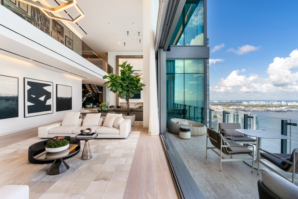 This is an example of an expansive contemporary mezzanine living room in Miami with light hardwood flooring, a standard fireplace, a stone fireplace surround and a built-in media unit.