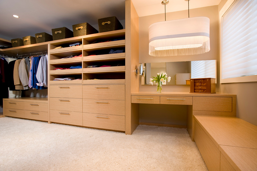 Photo of a large transitional gender-neutral dressing room in Boston with flat-panel cabinets, light wood cabinets, carpet and beige floor.